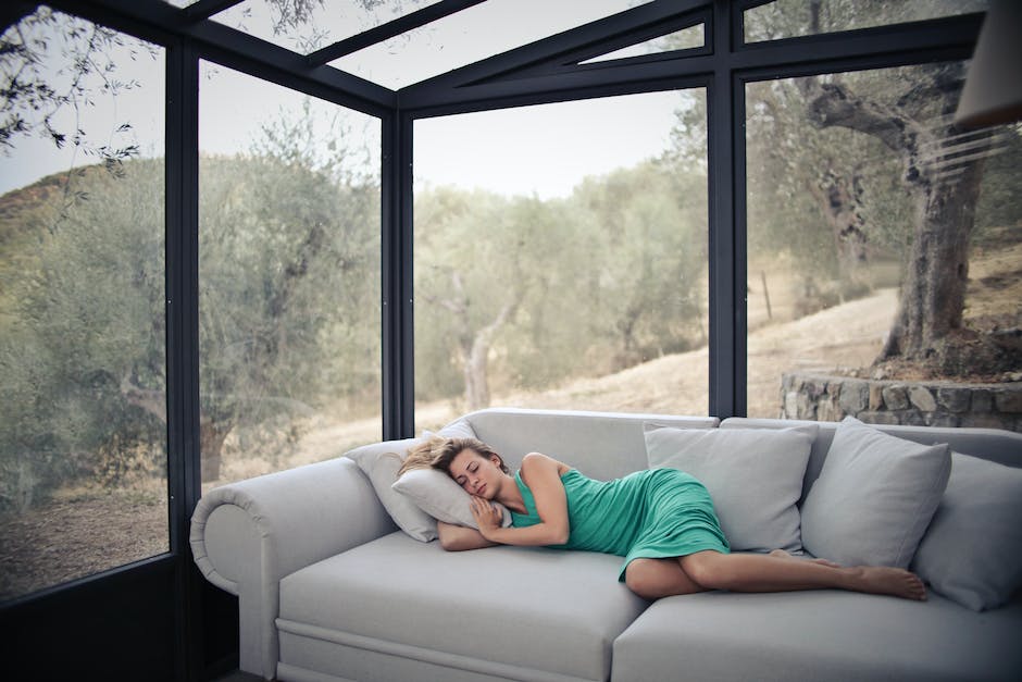 1684578294 woman sleeps on a couch with a view of trees outside large windows
