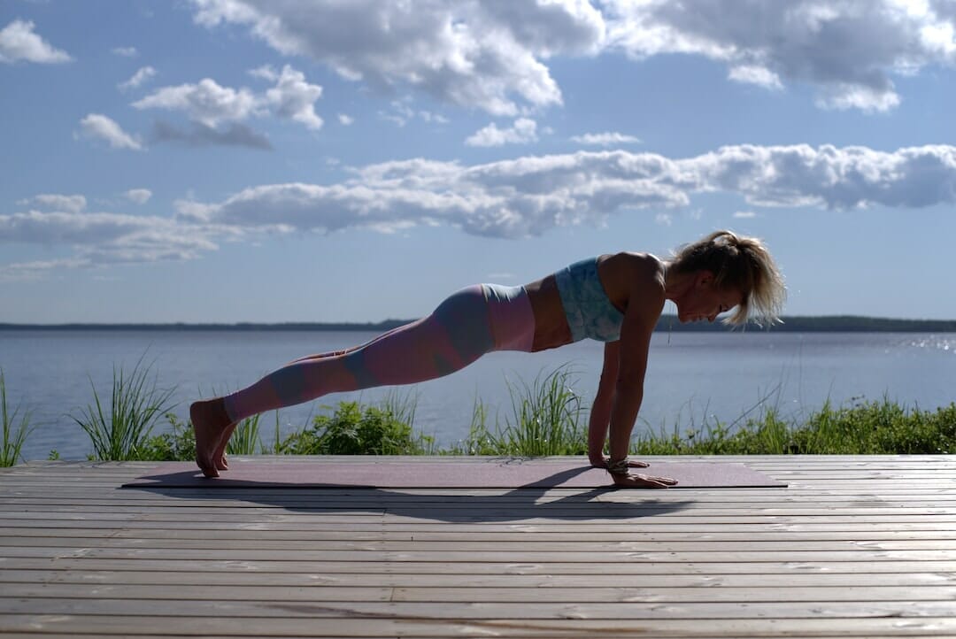 woman doing a plank on a mattress with an ocean view