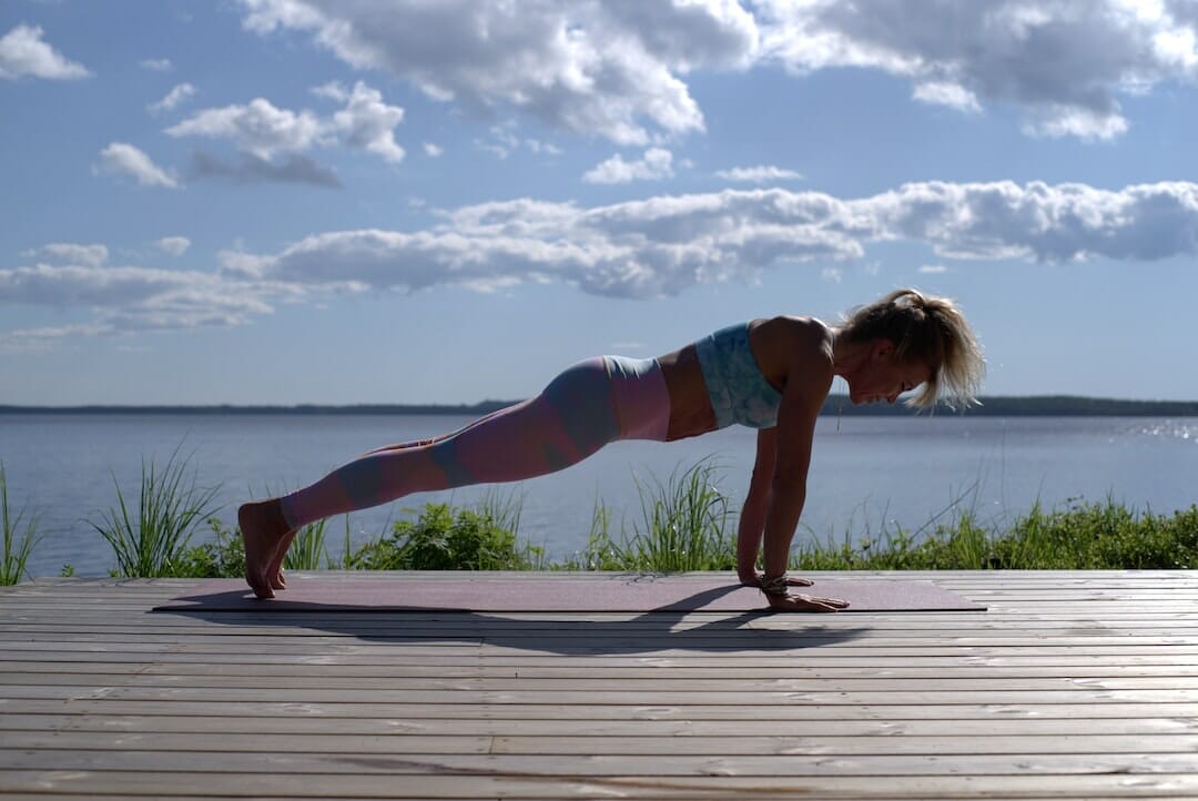 1684684218 woman doing a plank on a mattress with an ocean view