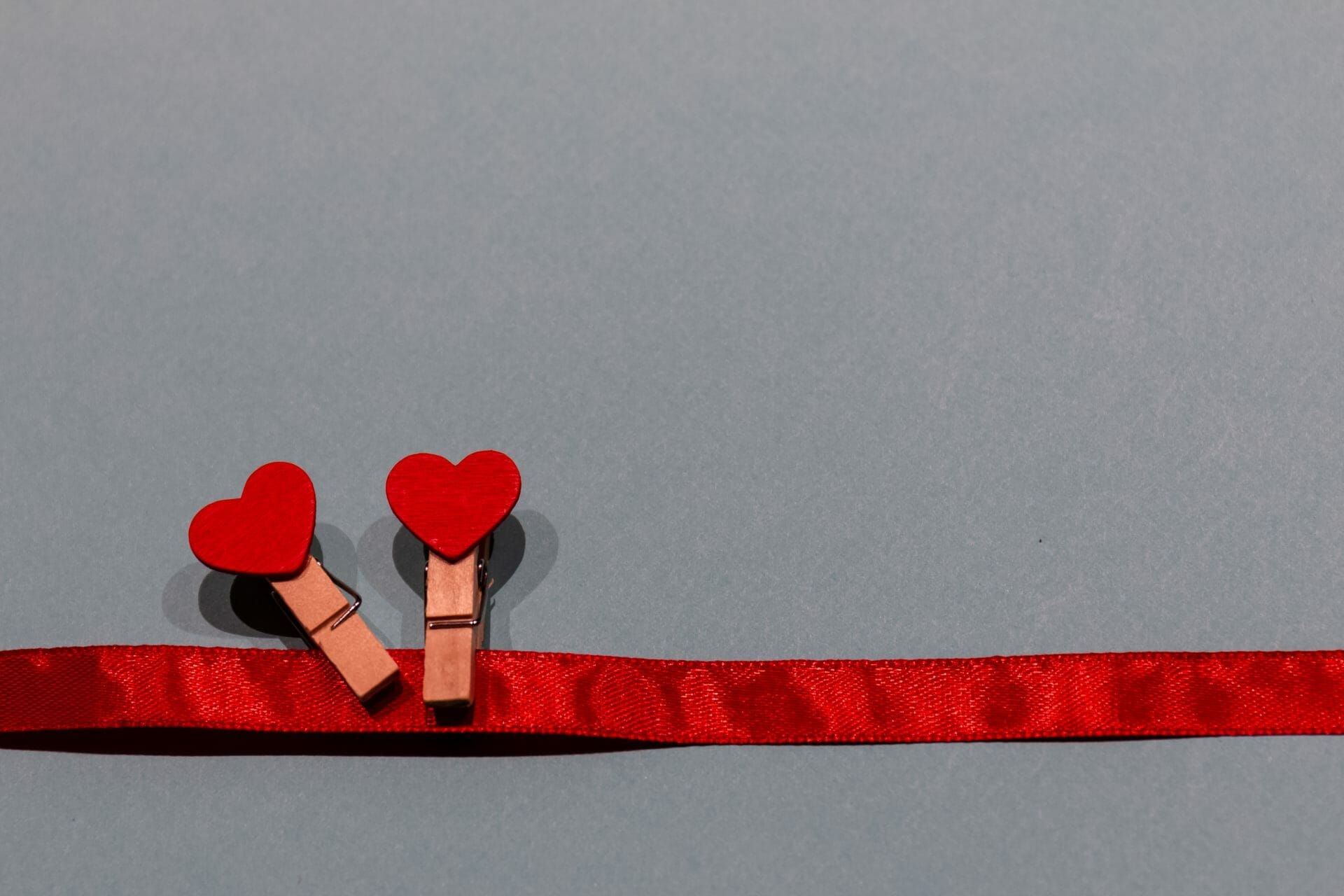 2 red hearts attached to clothes pegs on a red rope