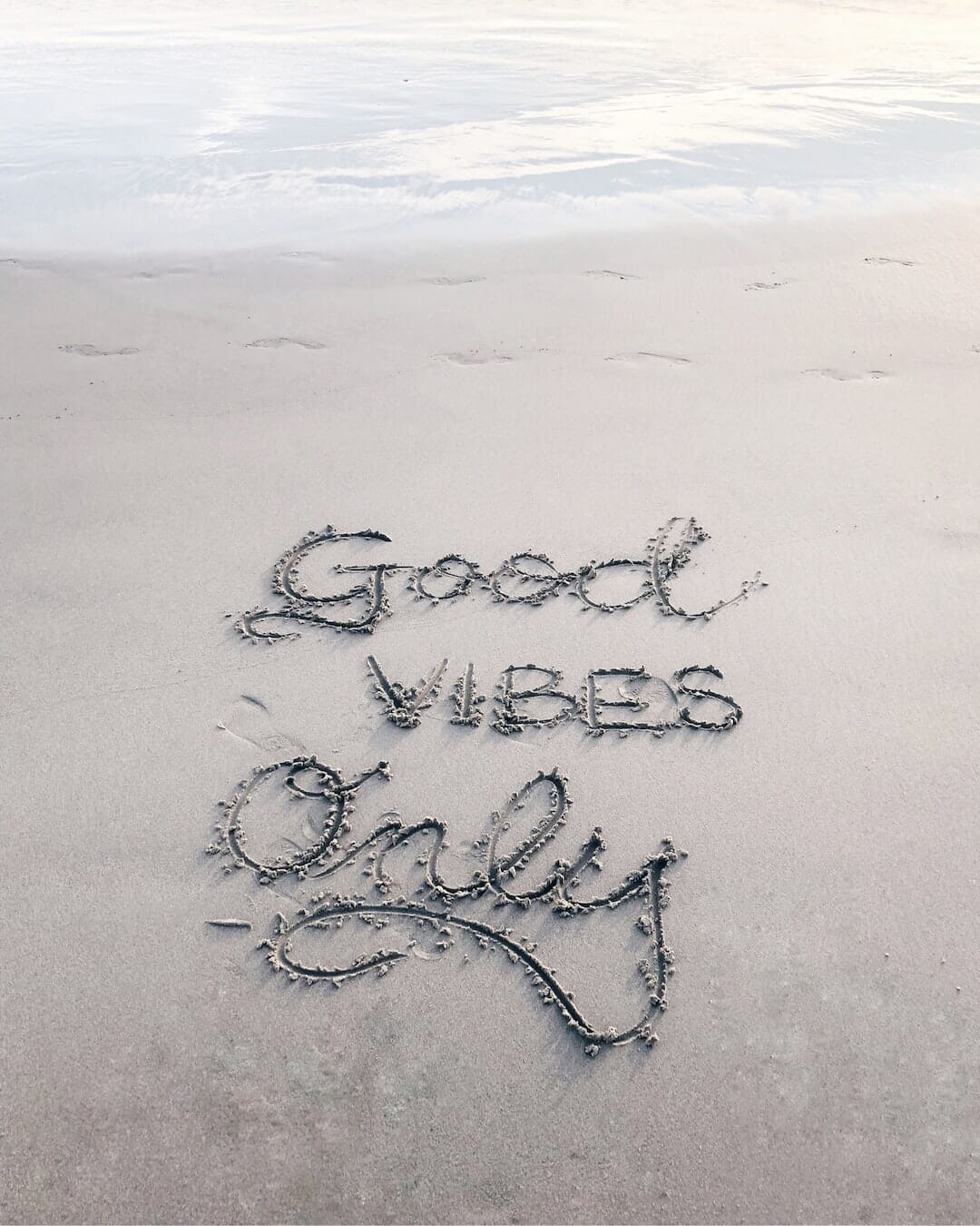 sentence written on sand on the beach "Good Vibes Only". 