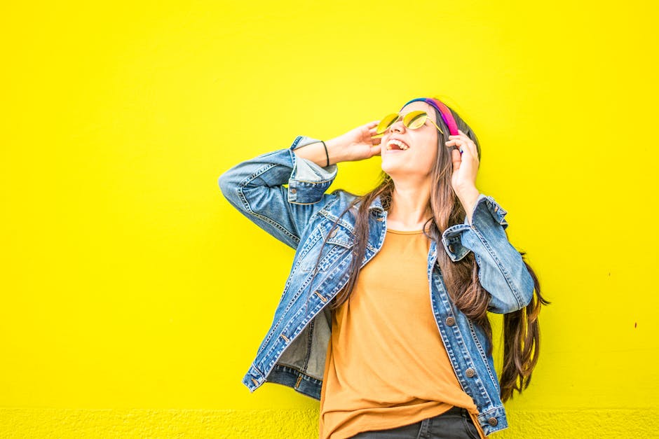 happy-positive woman smiling with sunglasses on a yellow background