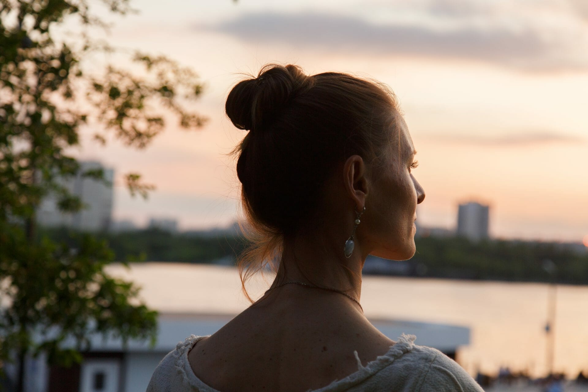 woman looks outside to the sunset, breathing and relaxing