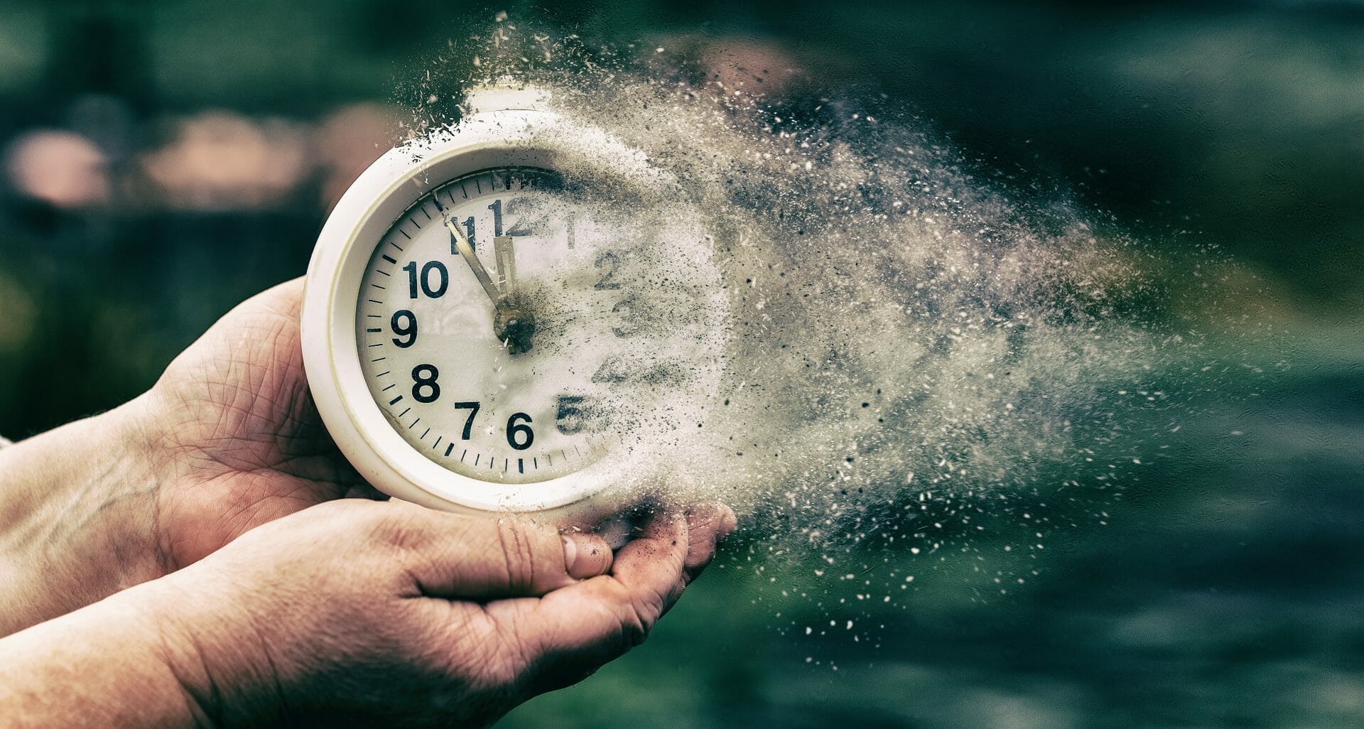 person holding white analog clock fading into dust