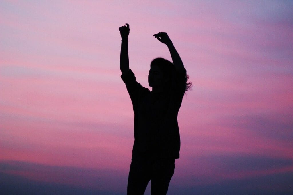 woman-spreads-her-arms-up-celebrating-with-the-sunset-on-the-background.-inspiring-and-motivation
